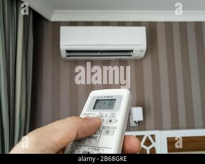 Remote control setting temperature for air conditioner on the wall Stock Photo