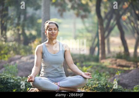 Woman practicing yoga in lotus position at park
