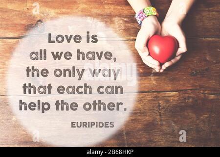 famous ancient Greek philosopher quote printed on vintage wooden board with red heart symbol in open hands Stock Photo