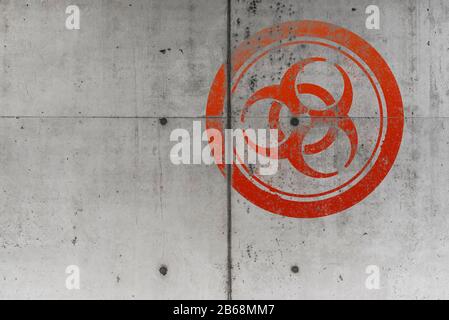 grungy red biohazard warning symbol on rough concrete wall background Stock Photo