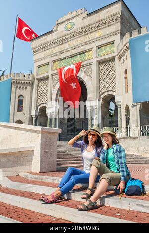 Two girl friends students sitting on the stairs near the main entrance of Istanbul University on Beyazit Square. Education in Turkey concept Stock Photo
