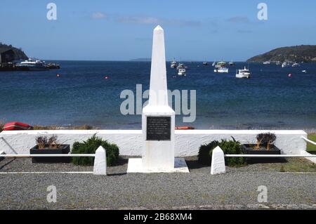 The war memorial on the seafront at Oban on Stewart Island, New Zealand. The obelisk looks out over the sea and Half Moon Bay. Stock Photo