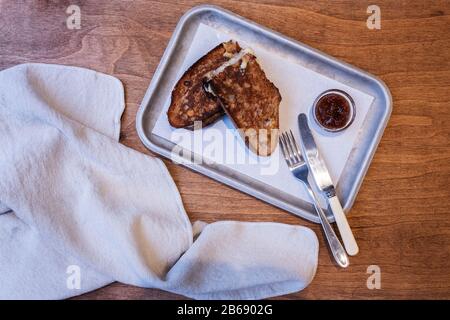 High angle close up of toasted slice of bread, jam and cutlery on tray in an artisan bakery. Stock Photo