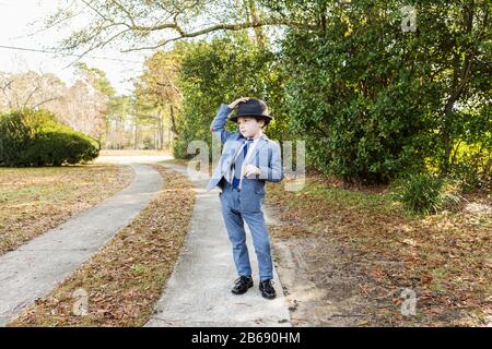 6 year old boy dressed in suit and wearing fedora, in driveway Stock Photo