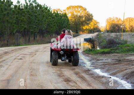 Two teenagers riding on a buggy, all terrain vehicle on a muddy track. Stock Photo