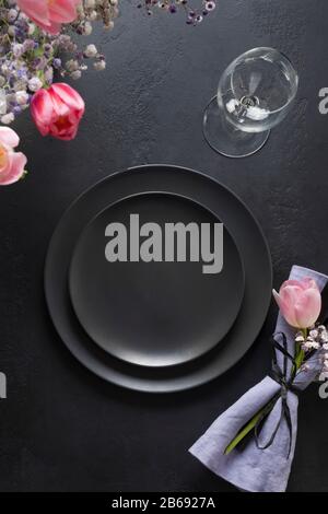 Elegance table setting spring pink tulips on black. Easter dinner. Top view. Stock Photo