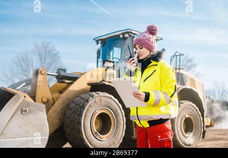 Woman with walkie talky on compost facility dispatching deliveries Stock Photo