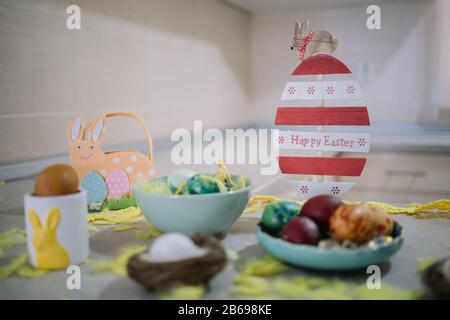 Easter decoration with painted eggs on kitchen countertop. Wooden egg decoration with rabbit on top and sight Happy Easter on kitchen counter with dec Stock Photo