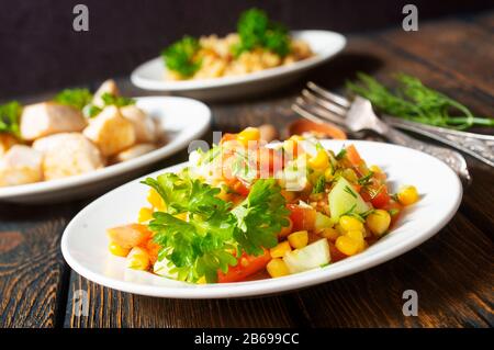 chicken roasted with vegetables and  bulgur sauce and fresh vegetable salad on wooden background Stock Photo