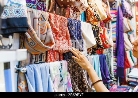 Young Woman Shopping For A New Scarf and choosing colorful fabric in bazar Stock Photo