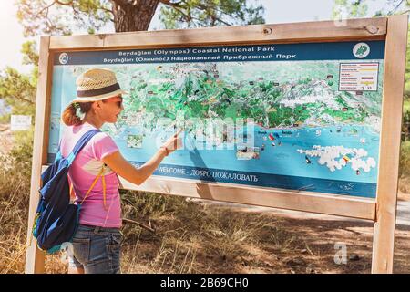 16 SEPTEMBER 2017, CIRALI, TURKEY: A young woman exploring the map of the national coastal park Olympos in Turkey, the concept of travel and hiking Stock Photo