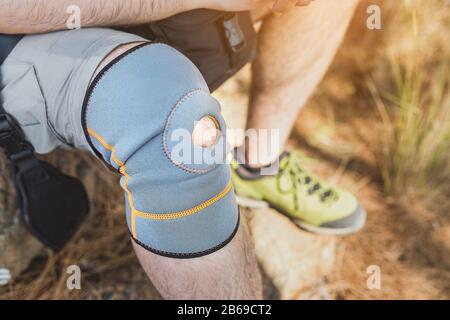 close up of knee support brace on leg of a traveler man during hiking outdoors in nature Stock Photo