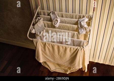 Little clotheshorse hanging on the radiator with towels, socks and a t-shirt (Pesaro, Italy, Europe) Stock Photo
