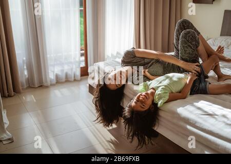 asian mother and daughter lying on the bed when enjoy playing together Stock Photo