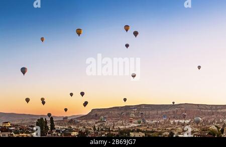 Many Hot air balloons flying over Goreme town in Cappadocia, panoramic view Stock Photo