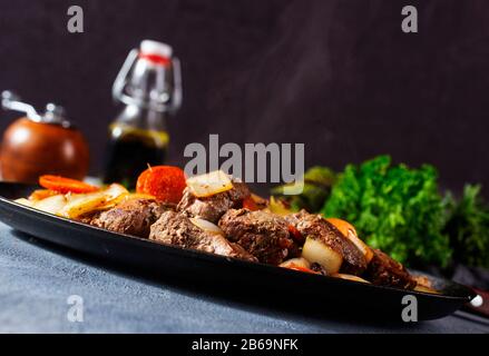 fried liver with potato and vegetables on metal plate Stock Photo
