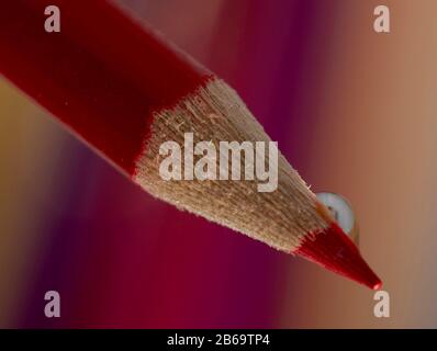 Macro of wooden crayon on colorful background with water drop Stock Photo