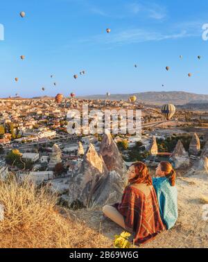 Couple of friends travelers enjoying valley view with wonderful balloons flight over Cappadocia valley in Turkey Stock Photo