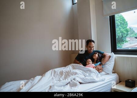 two daughters and their father sit on the bed when they wake up Stock Photo