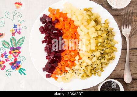 Plate of beetroot salad of boiled organic homegrown vegetables over on old-fahioned embroidered napkin on old wooden tabletop. Top view. View from abo Stock Photo