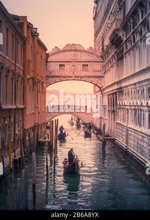 Gondoliers row under the Bridge of Sighs in Venice, Italy on an atmospheric and cold winter afternoon in December Stock Photo