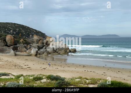 Couple on the beach at Whisky Beach.  Massive granite boulders adorn the coast like natural sculptures Stock Photo
