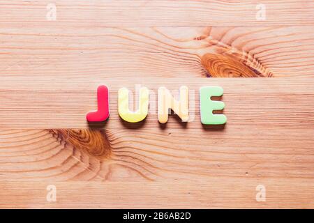 June word written with colorful letters on wooden background, top view Stock Photo