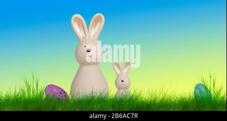 two easter bunnys stand on a meadow with easter eggs Stock Photo