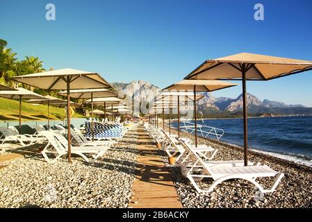 Sunshades and chaise lounges on beach. Turkey, Kemer. Beautiful view of mountains and sea