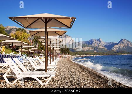 Sunshades and chaise lounges on beach. Turkey, Kemer. Beautiful view of mountains and sea