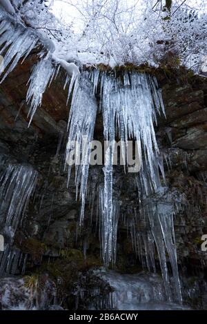 Crystal clear sharp icicles hanging down on the mountain Stock Photo