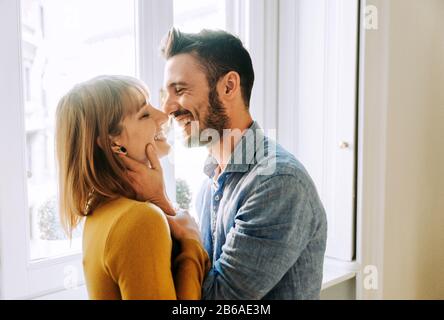 Two young adults at home - Romantic moment at home, couple of lovers kissing Stock Photo