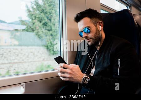 Young man traveling by train wearing earphones Stock Photo