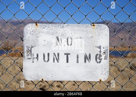 no hunting sign wired to a chain link fence Stock Photo