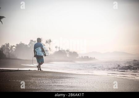 Surfer on a beach headed towards the ocean. Stock Photo