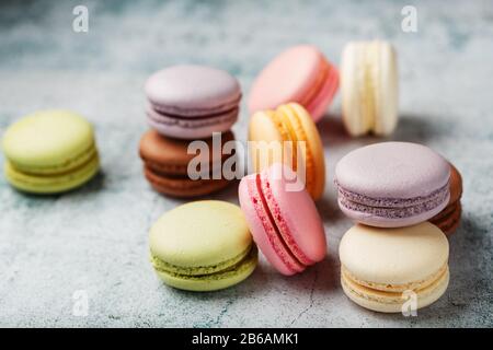 Multicolored macaroni cookies lie on a gray stone slab. Still-life of confectionery products. Stock Photo