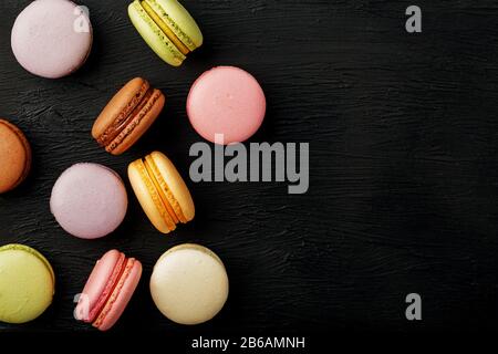 Macaroni cookies lie on a black textured background. Free space. Still-life of confectionery products. Stock Photo