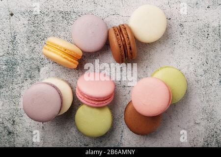 Multicolored macaroni cookies lie on a gray stone slab. Still-life of confectionery products. Stock Photo
