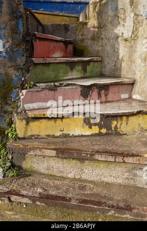 An old shabby and faded spiral staircase made of concrete with a rainbow color, located in the street in the Turkish city of Istanbul. Stock Photo