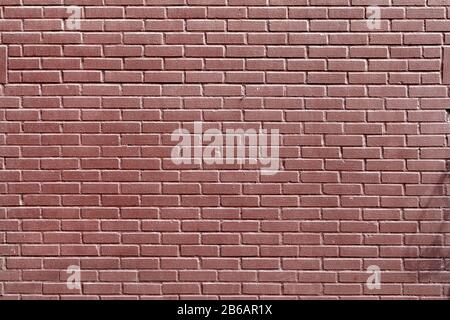Fence or wall of red decorative brick with a smooth glazed surface. Abstract texture for background. Stock Photo