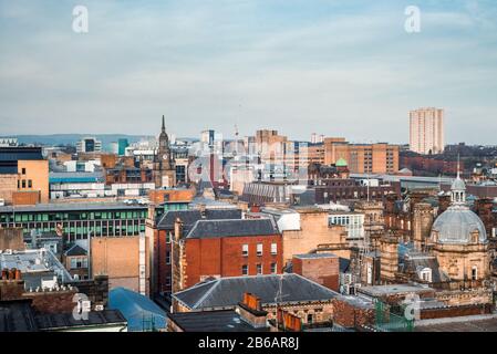 A wide rooftop view looking out over the buildings and architecture of Glasgow city centre in evening light, Scotland
