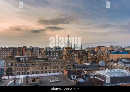 A wide rooftop view looking out over the buildings and architecture of Glasgow city centre at sunset, Scotland