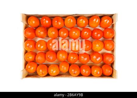 Persimmon fruit in the wooden box isolated on white. Clipping Path included. Juicy ripe persimmon in a large wooden box on a white background. Stock Photo
