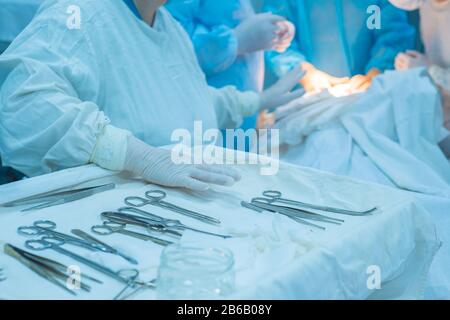 closeup, the hands of a nurses hand, an assistant surgeon takes a surgical instrument from a sterile table. In a sterile operating room. Removing a ma Stock Photo