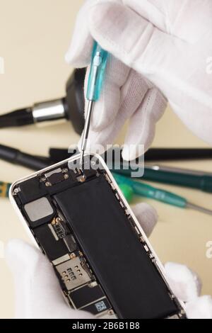 Hands of the master phone repair disassemble screwdriver smartphone. Profession Stock Photo