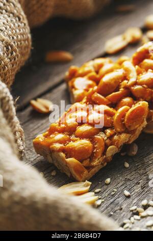 Sweets bar of peanuts on a vintage background with burlap. Delicious oriental sweets Gozinaki from sunflower seeds, sesame and peanuts, covered with Stock Photo
