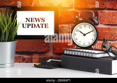 NEWS UPDATE text with alarm clock, books and vase on brick background. Business, Quotes and Copy Space concept Stock Photo