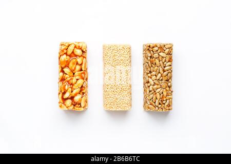 Grain granola bar with peanuts, sesame and seeds in a row on a white background. Top view Three assorted bars, isolate Stock Photo