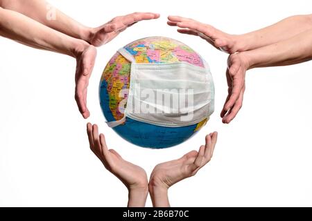 Save The World From The Coronavirus.  Hands around the Earth globe with a protective mask , save or protect the planet, isolated on white background. Stock Photo