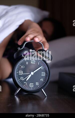 Wake up asleep young woman stopping alarm clock on cozy bed in morning Stock Photo